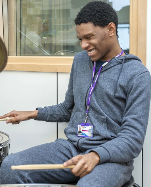 Young man smiling while playing the drums enthusiastically in a music room. Young man smiling while playing the drums enthusiastically in a music room.
